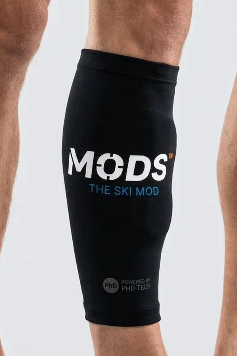 Black MODS ski knee support sleeve fitted around a skier’s lower leg.