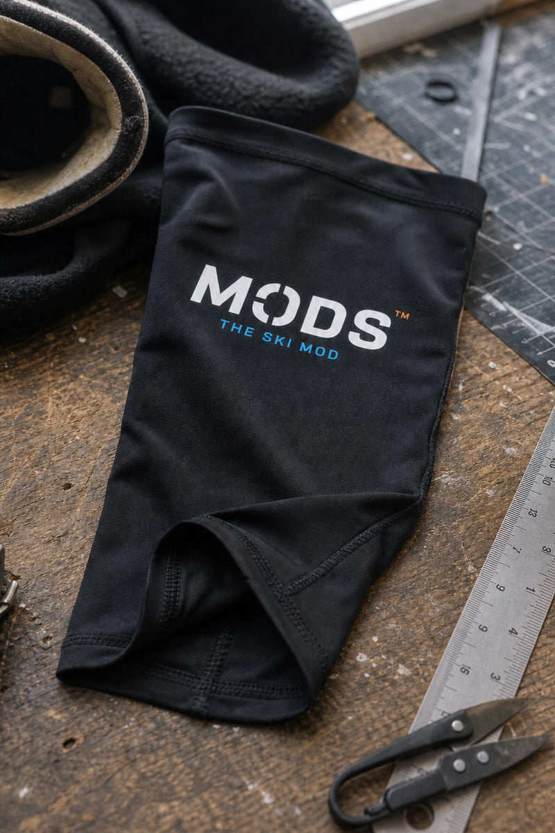 Black MODS lower-leg sleeve displayed beside a metal ruler and fabric scissors on a wooden workbench.