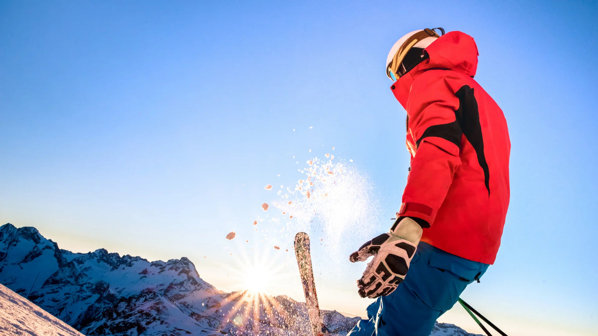 Skier in red jacket carving through snow in bright alpine conditions